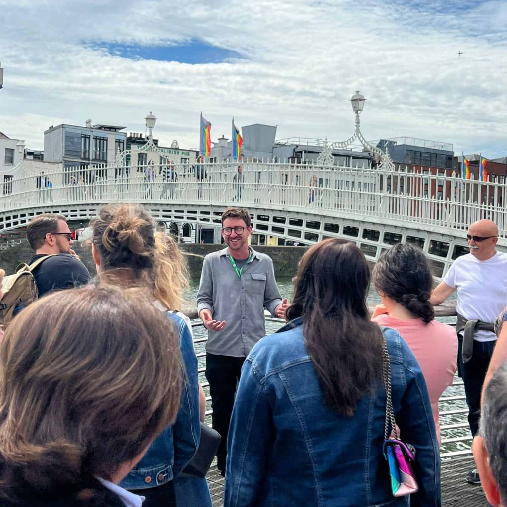 Dublin Tour guide laughs with tourists at Dublins Ha'Penny Bridge