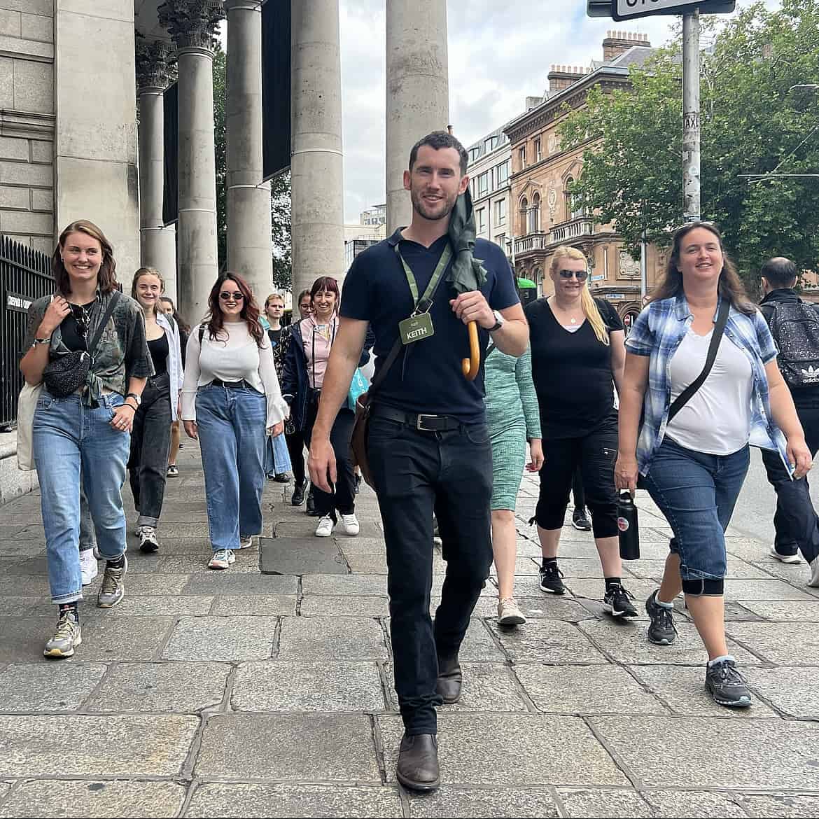 Dublin tour guide leads group past Old Parliament building on College Green.